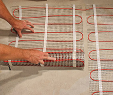 Roll out the floor heating mat and secure it to the subfloor for the next row.